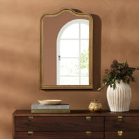 Etta Mirror in raw antique brass iron with a scalloped edge, reflecting natural light.
