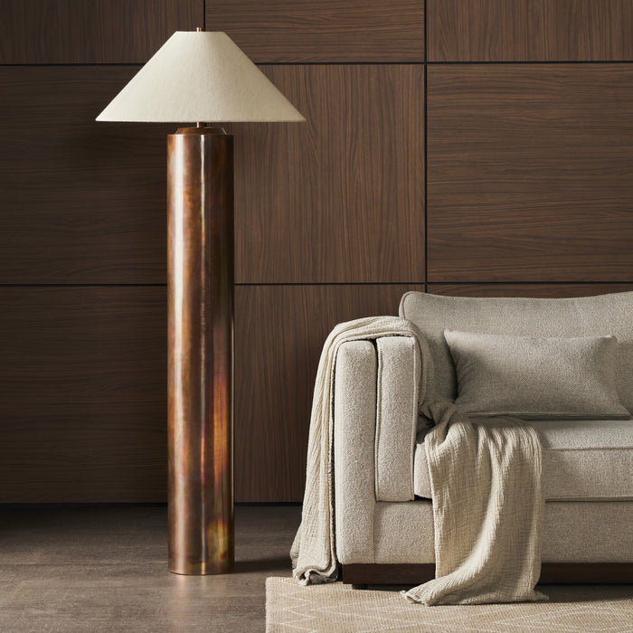 Iridescent acid wash floor lamp with a conical shade beside a cozy couch.