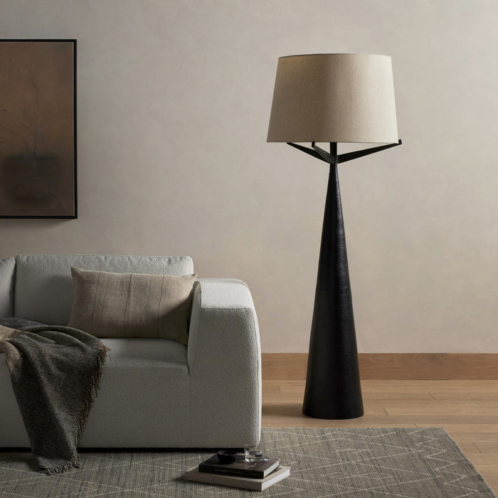 Hammered black aluminum floor lamp with a soft fabric shade in a cozy living room scene.