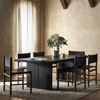 Sevilla Dining Table in worn black oak with minimalist design and matching chairs.