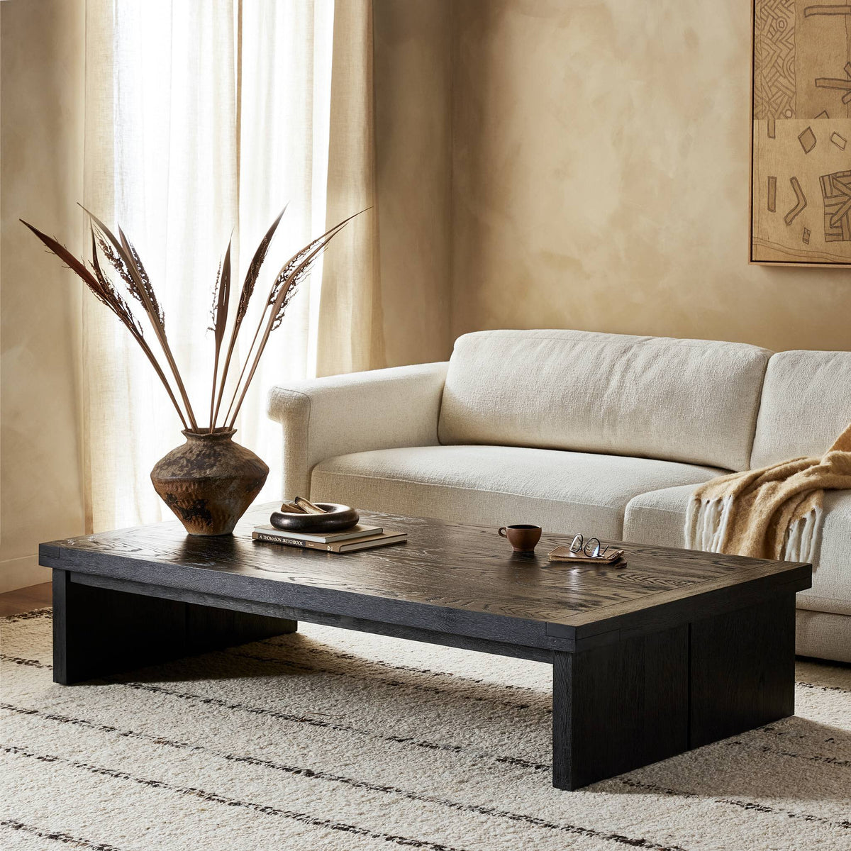 Darby Coffee Table in worn black with a textured surface, styled in a cozy living room.
