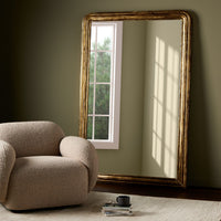 Vesper Louis Floor Mirror with antiqued gold leaf frame leaning against a wall.