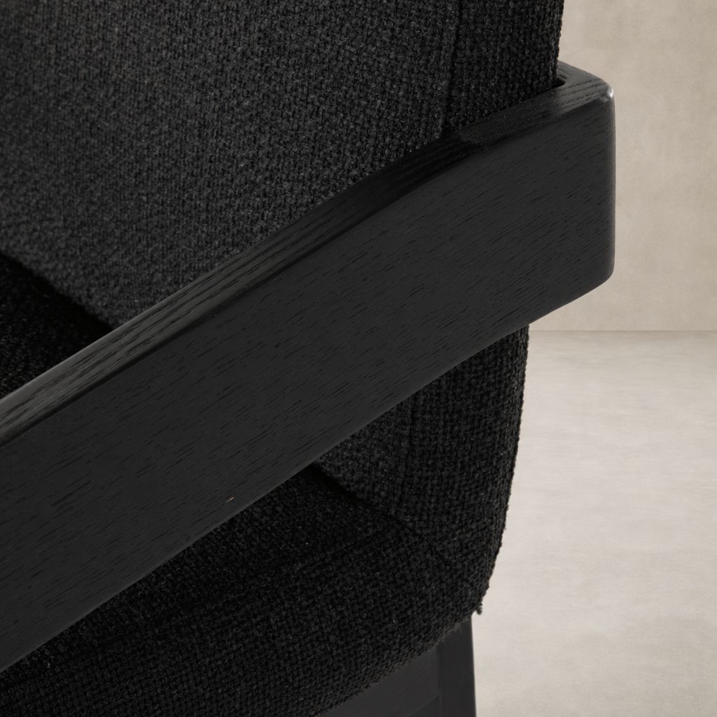 Close-up of a Gibson Black dining armchair showcasing textured fabric and sleek wooden armrests.