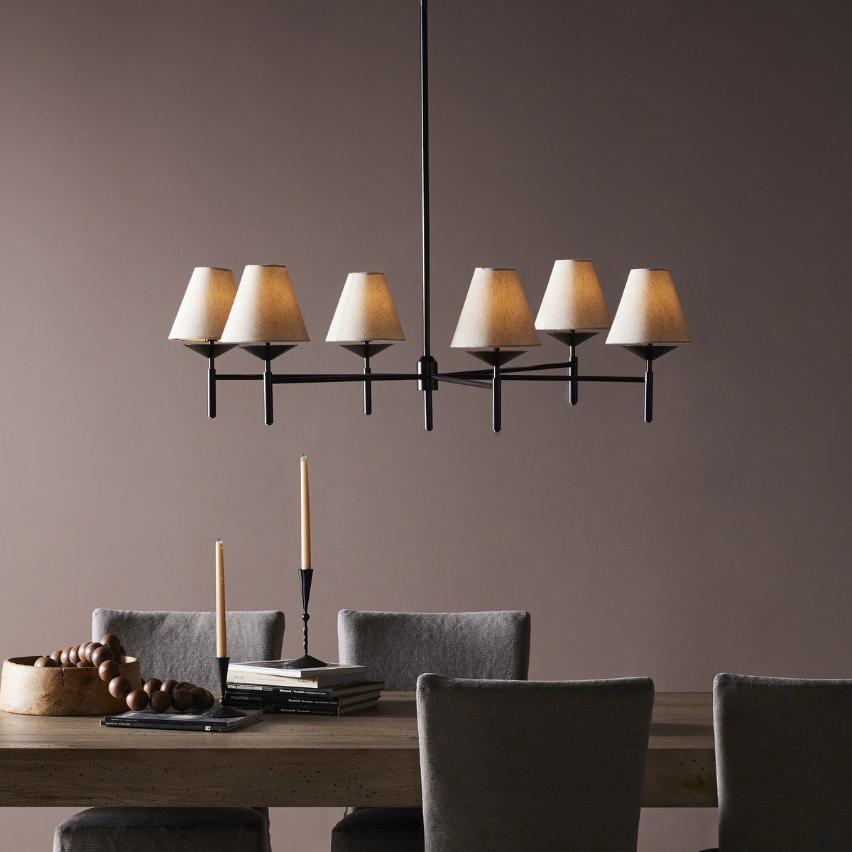 Jet black chandelier with conical shades, illuminating a modern dining space.