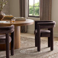 Tivoli Dining Chair in Surrey Cocoa, featuring smooth curves and plush upholstery, elegantly placed by a wooden table.