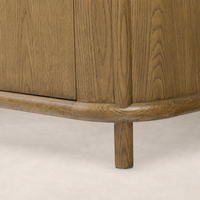 Close-up of the Laurent Sideboard in Amber Oak, showcasing its smooth rounded base and natural wood grain.