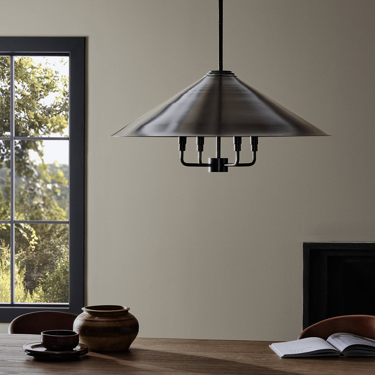 Antique brass iron chandelier with a sleek conical shade over a dining table.