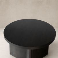 Rumi End Table with a sleek, round black top and sturdy base.