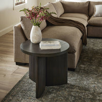 Rumi End Table in dark wood finish with a round top and modern design, styled beside a sofa.