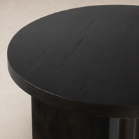 Rumi End Table with a smooth, round black wood top featuring textured surface details.