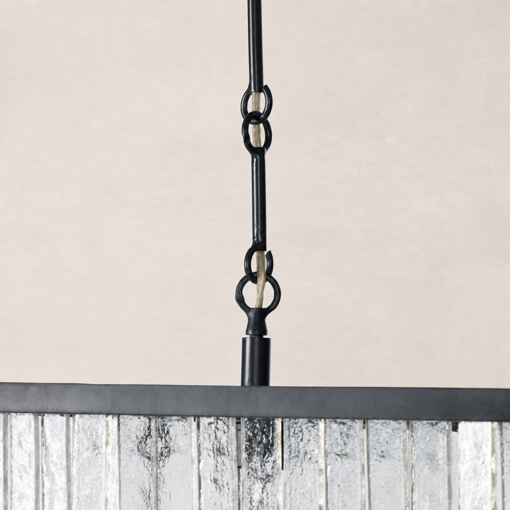 Antiqued iron linear chandelier showcasing chain detail and reflective glass panel.
