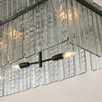 Antiqued iron linear chandelier with textured glass panels and exposed bulbs.