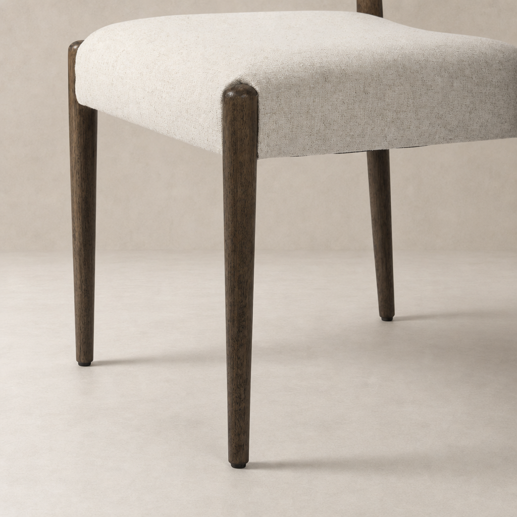 Mira Armless Dining Chair with Antwerp Natural fabric and sleek wooden legs.