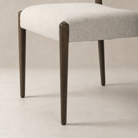 Mira Armless Dining Chair with Antwerp Natural fabric and sleek wooden legs.
