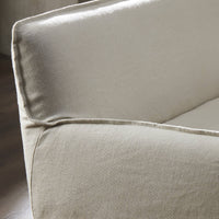 Slipcovered upholstered bench in cream fabric with a low back and wood legs.