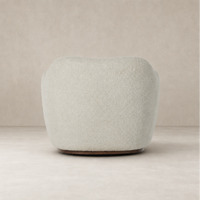 Poppy Swivel Chair in Sheldon Ivory featuring a plush rounded design and wooden base.