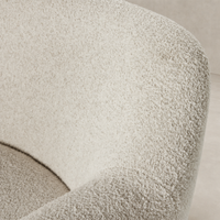 Textured Sheldon Ivory upholstery of the Poppy Swivel Chair showcasing its curved design.