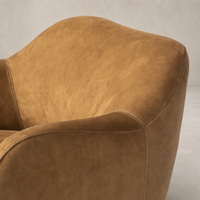 Close-up of the Poppy Swivel Chair in Nubuck Cognac, featuring soft curves and stitching details.