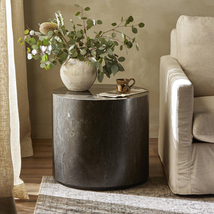 Keller End Table with a sleek, round design and dark stone finish in a cozy living room setting.
