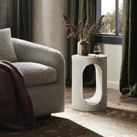 Atlas End Table with a circular design and open cutout, set beside a cozy sofa.