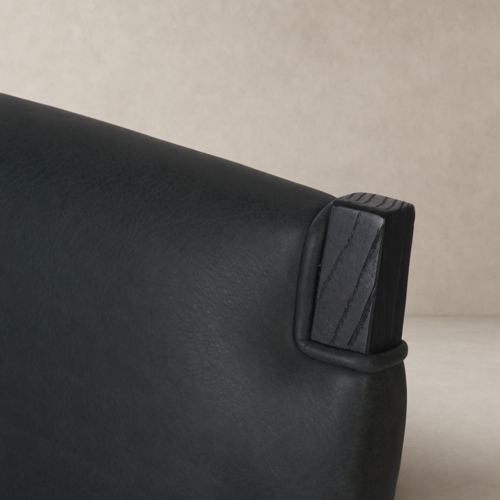 Close-up of the Nori Dining Chair showing the Brickhouse Black leather and wooden detail.