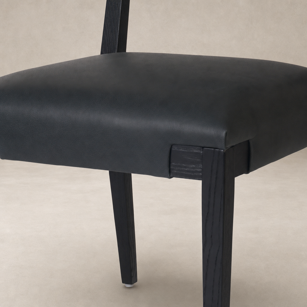 Nori Dining Chair in Brickhouse Black with sleek leather seating and sturdy wooden legs.
