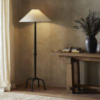Matte black cast aluminum floor lamp with a conical shade in a cozy setting.