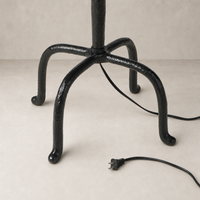 Matte black cast aluminum floor lamp base with curved legs and power cord.
