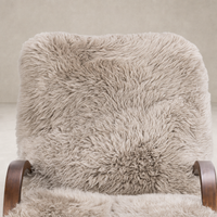 Livia Chair in taupe Mongolian fur with soft, textured upholstery and wooden armrests.