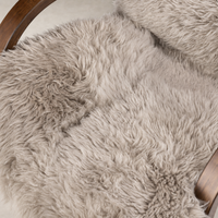 Close-up of Livia Chair featuring soft taupe Mongolian fur upholstery and curved wooden arm.