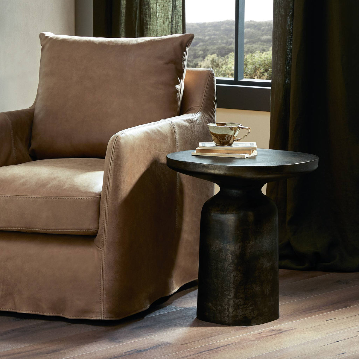Odette End Table with a smooth black finish, paired with a cozy leather chair.