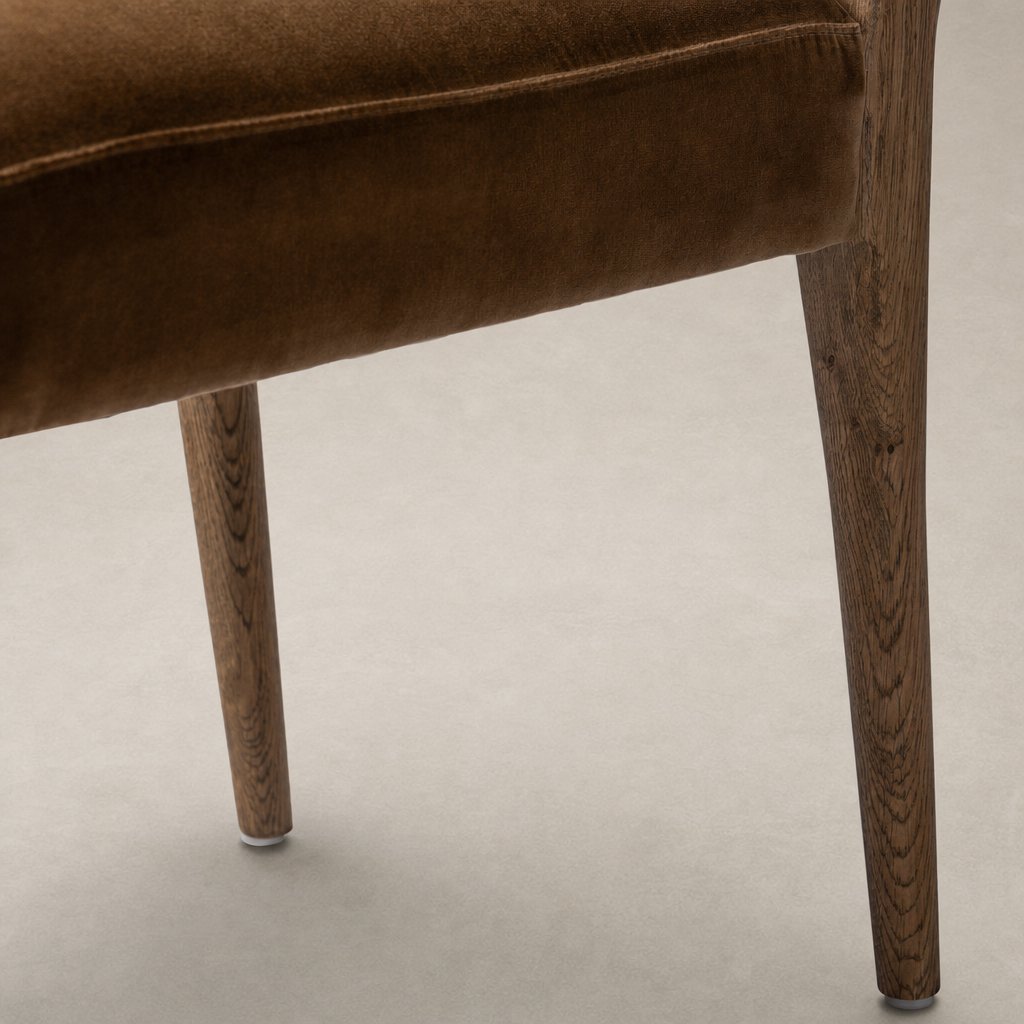 Close-up of Marfa Dining Chair in Surrey Ochre, featuring soft upholstery and sturdy wooden legs.
