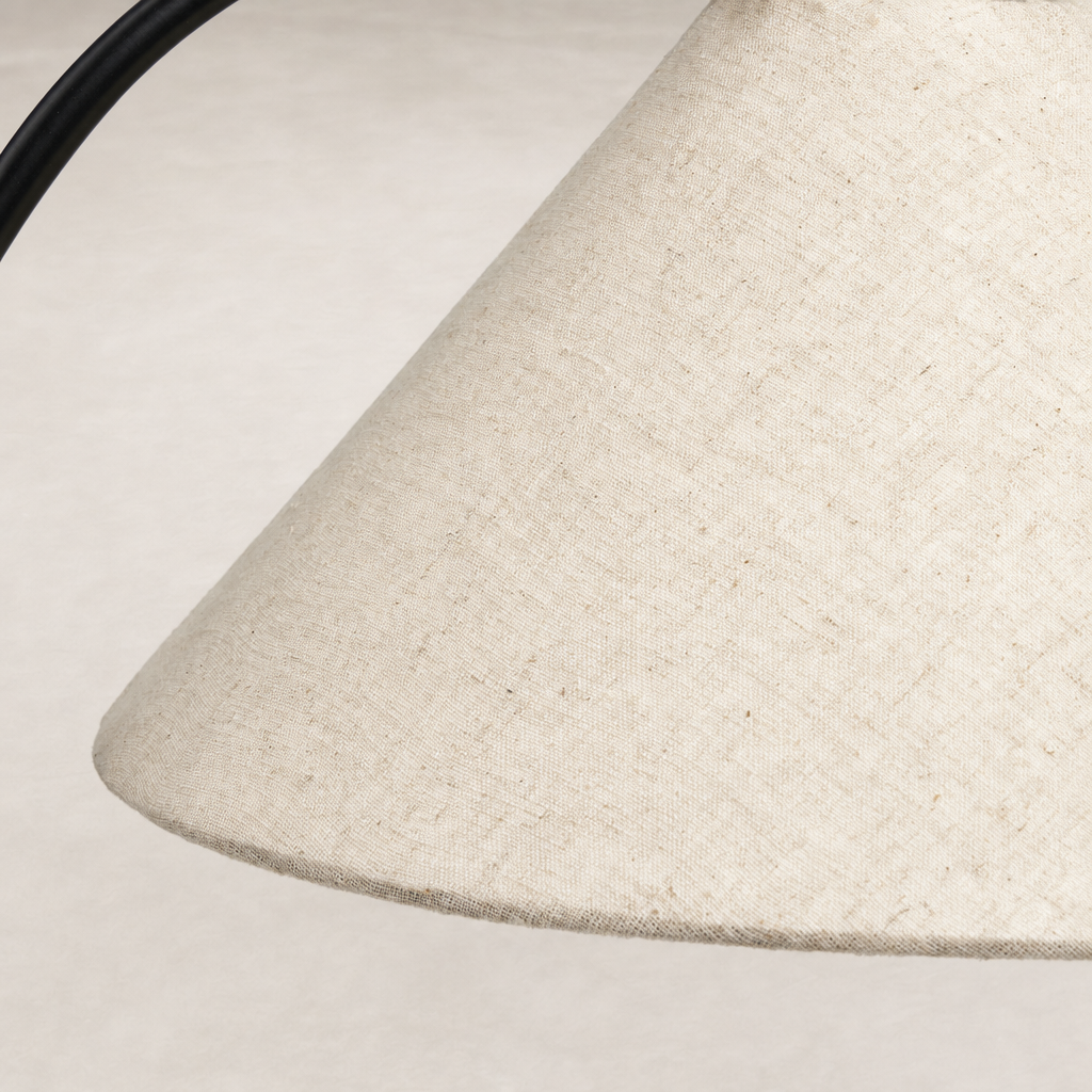 Close-up of a matte black table lamp with a textured beige fabric shade.