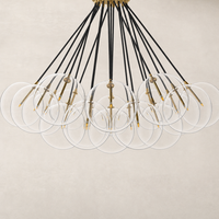 Burnished brass chandelier with clear circular shades and black cords.
