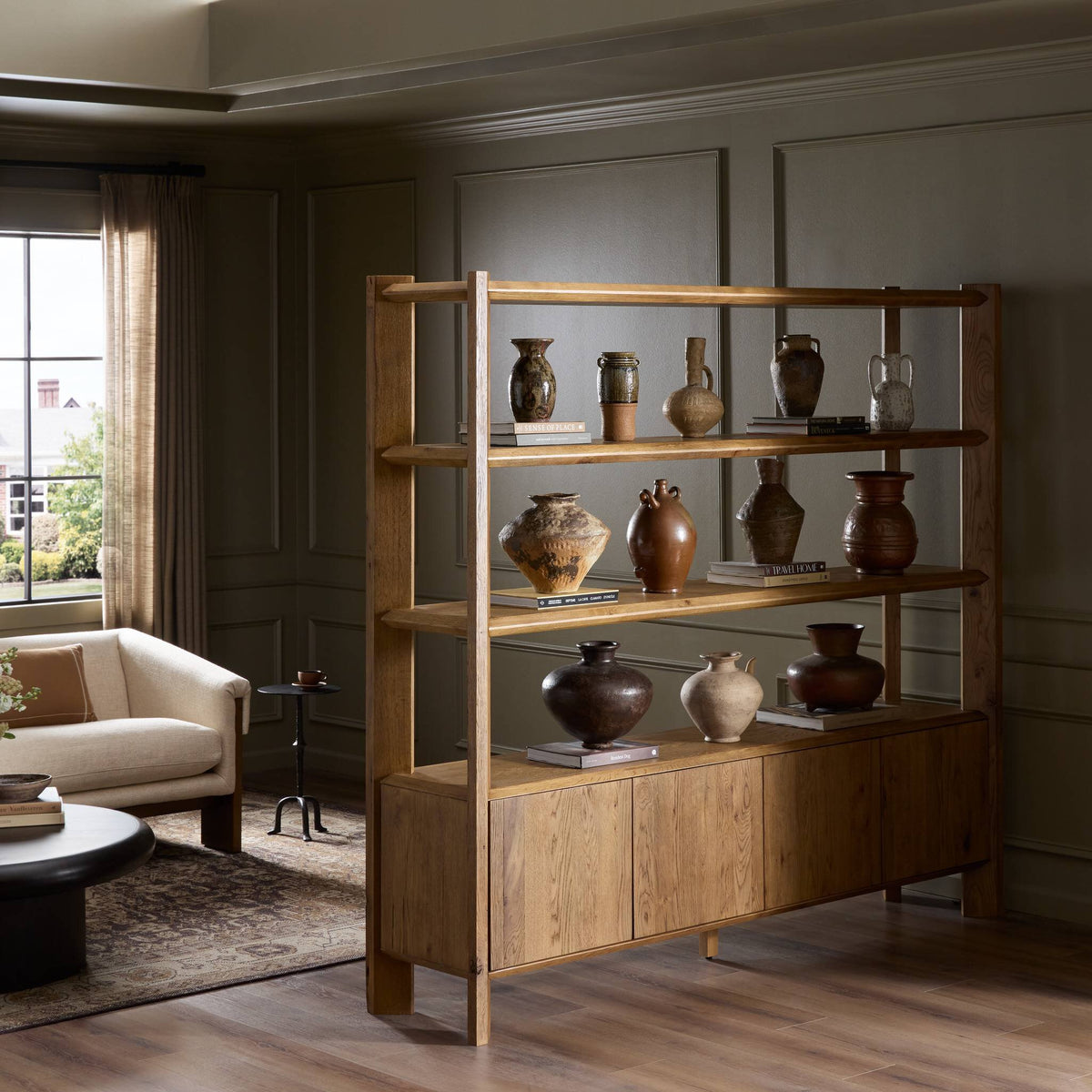 Zuma Wide Bookshelf in Worn Oak with decorative pottery displayed in a stylish living room.