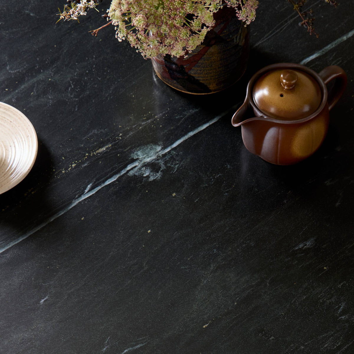 Ilaria Round Dining Table 42 with elegant black marble top and decorative accents.