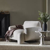 Front view of the Elba Accent Chair in a cozy setting, featuring soft, textured upholstery and rounded shapes.