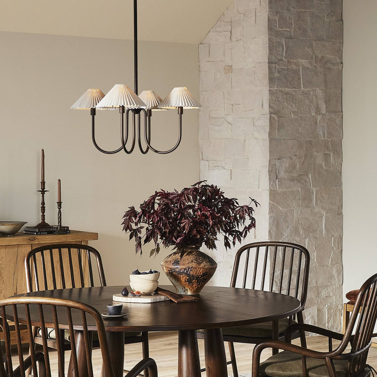 Light oil rubbed bronze chandelier with pleated shades above a dining table.