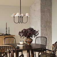Light oil rubbed bronze chandelier with pleated shades above a dining table.