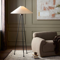 Matte black floor lamp with a conical shade, styled in a cozy room setting.