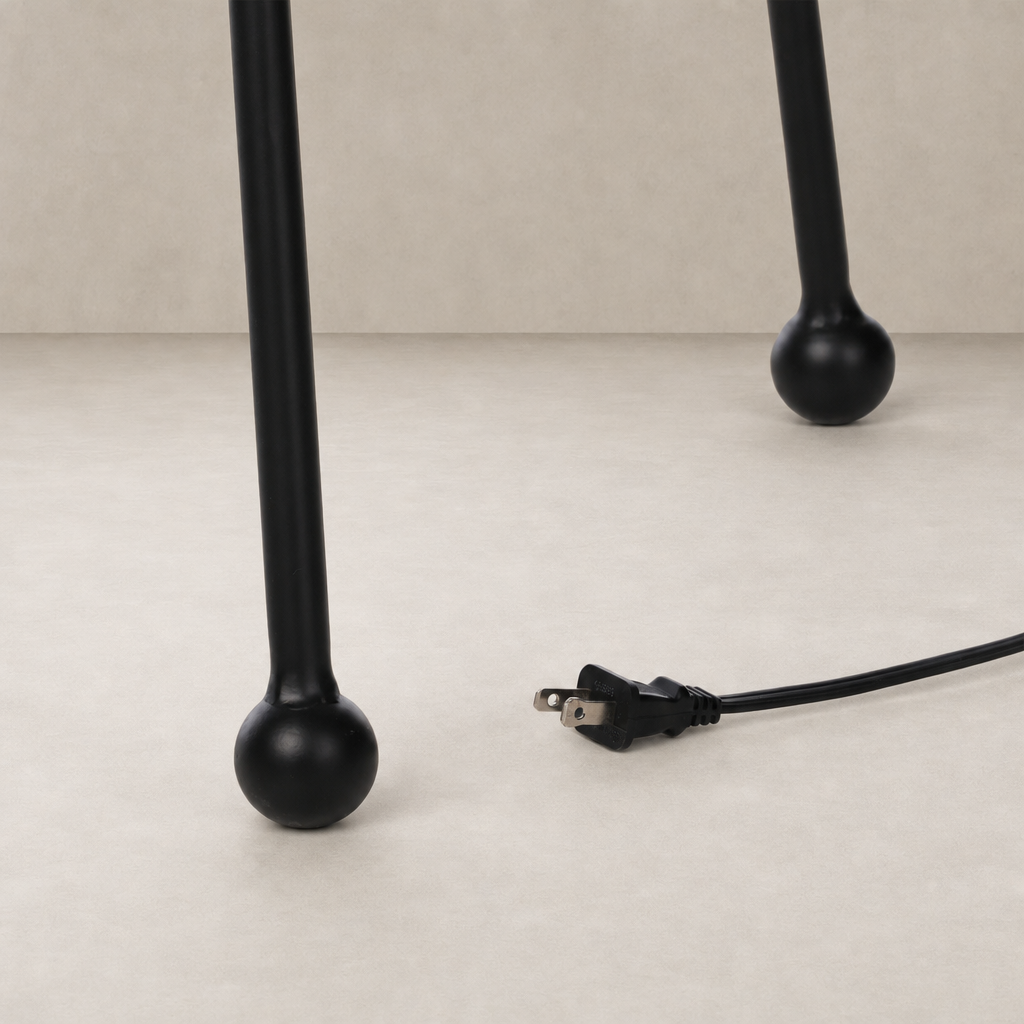 Matte black floor lamp base with rounded feet and electrical cord.