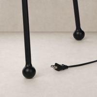 Matte black floor lamp base with rounded feet and electrical cord.