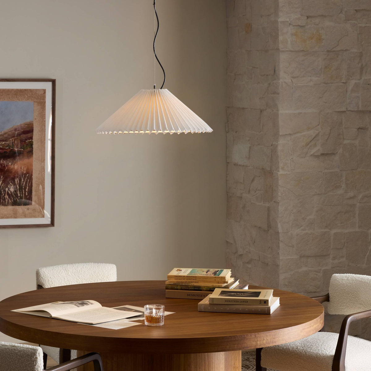 Jet black pendant light with pleated design hanging above a wooden table.