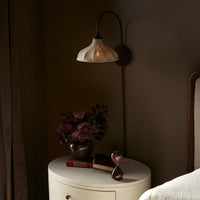 Waverly Sconce in light oil rubbed bronze with softly curved shade beside a vase.
