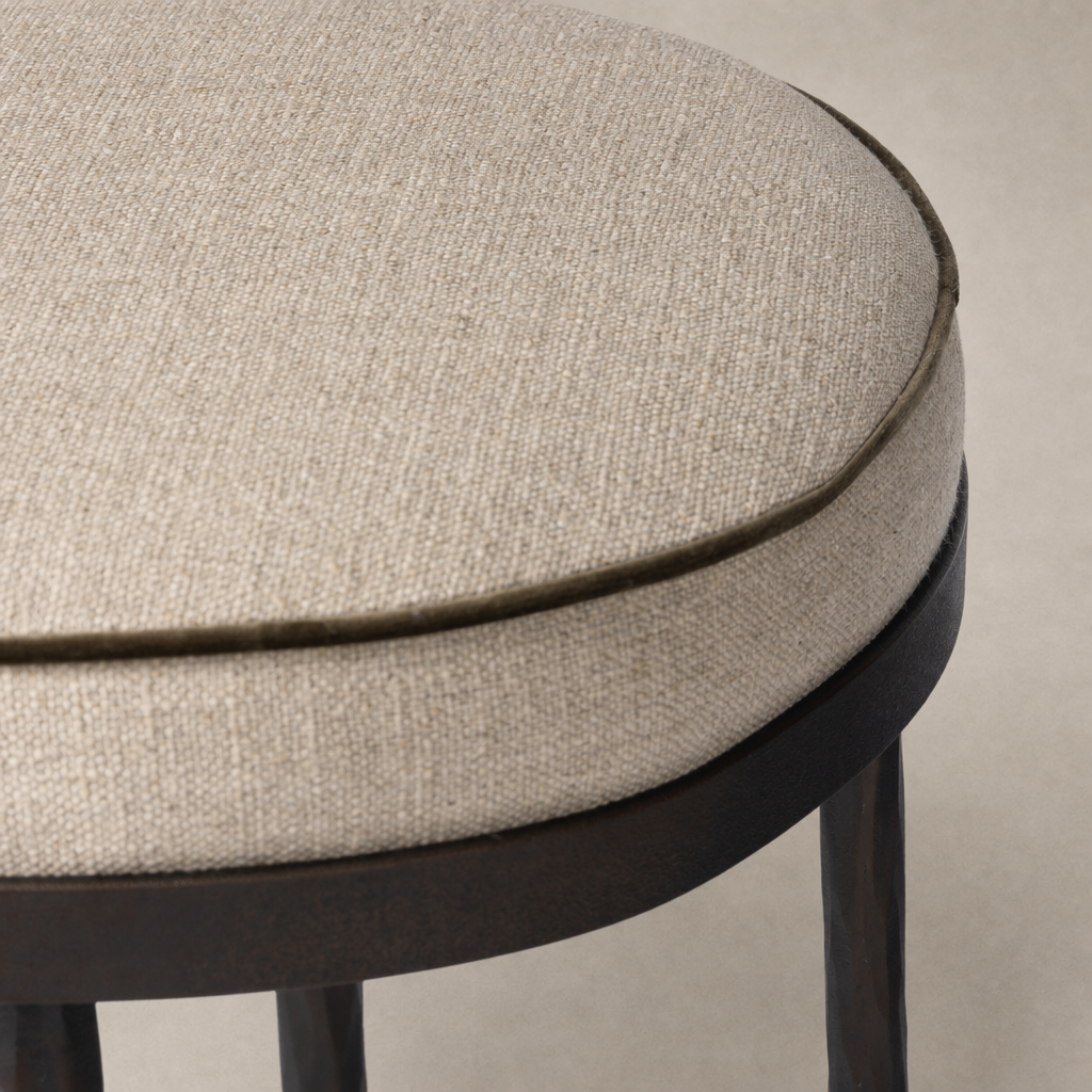 Close-up of the Jasper Bar + Counter Stool in Alcala Taupe, showcasing its textured fabric and round shape.