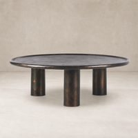 Cade Coffee Table in distressed bronze featuring a round top and three cylindrical legs.