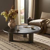Distressed bronze Cade Coffee Table with a round top and sturdy pedestal legs.