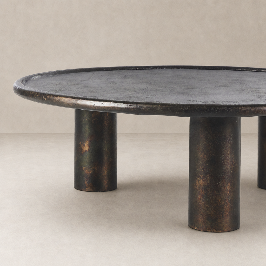 Cade Coffee Table featuring a round shape and distressed bronze finish.