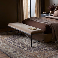 Long upholstered bench with a warm brown cushion and hand-forged iron base in bedroom