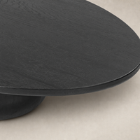 Ronan Coffee Table in worn black features a smooth, rounded top and curved base.